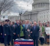 Image of a group of people in front of the Capital and behind a banner reading, "The Charitable Act."